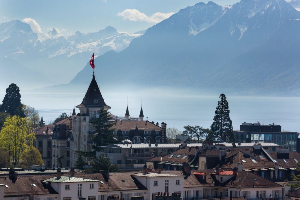 Image of a rooftop view of Lausanne, with Lake Geneva and the Swiss Alps in the background 