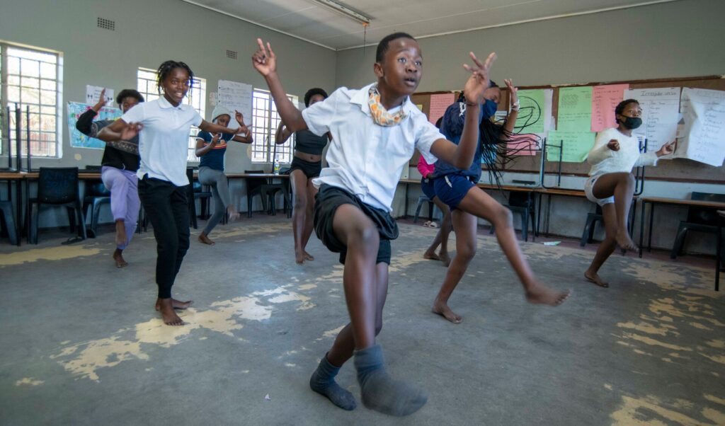Image of school children dancing in sync in a classroom 
