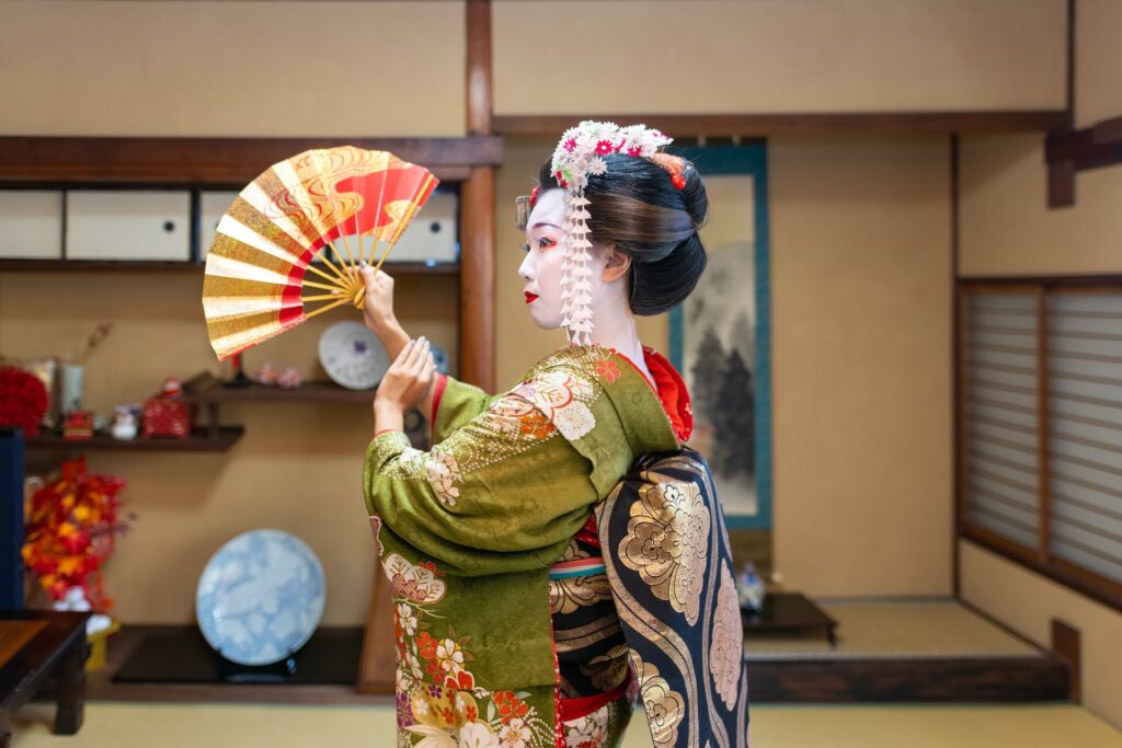 Image of a Maiko (Geisha in training) dancing with 'Sensu' folding fan in Japanese tatami room