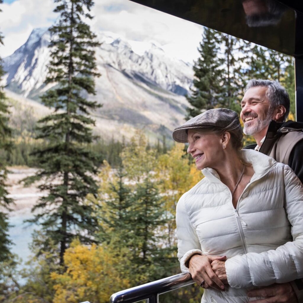 couple standing on the outdoor platform looking at the views aboard the Rocky Mountaineer
