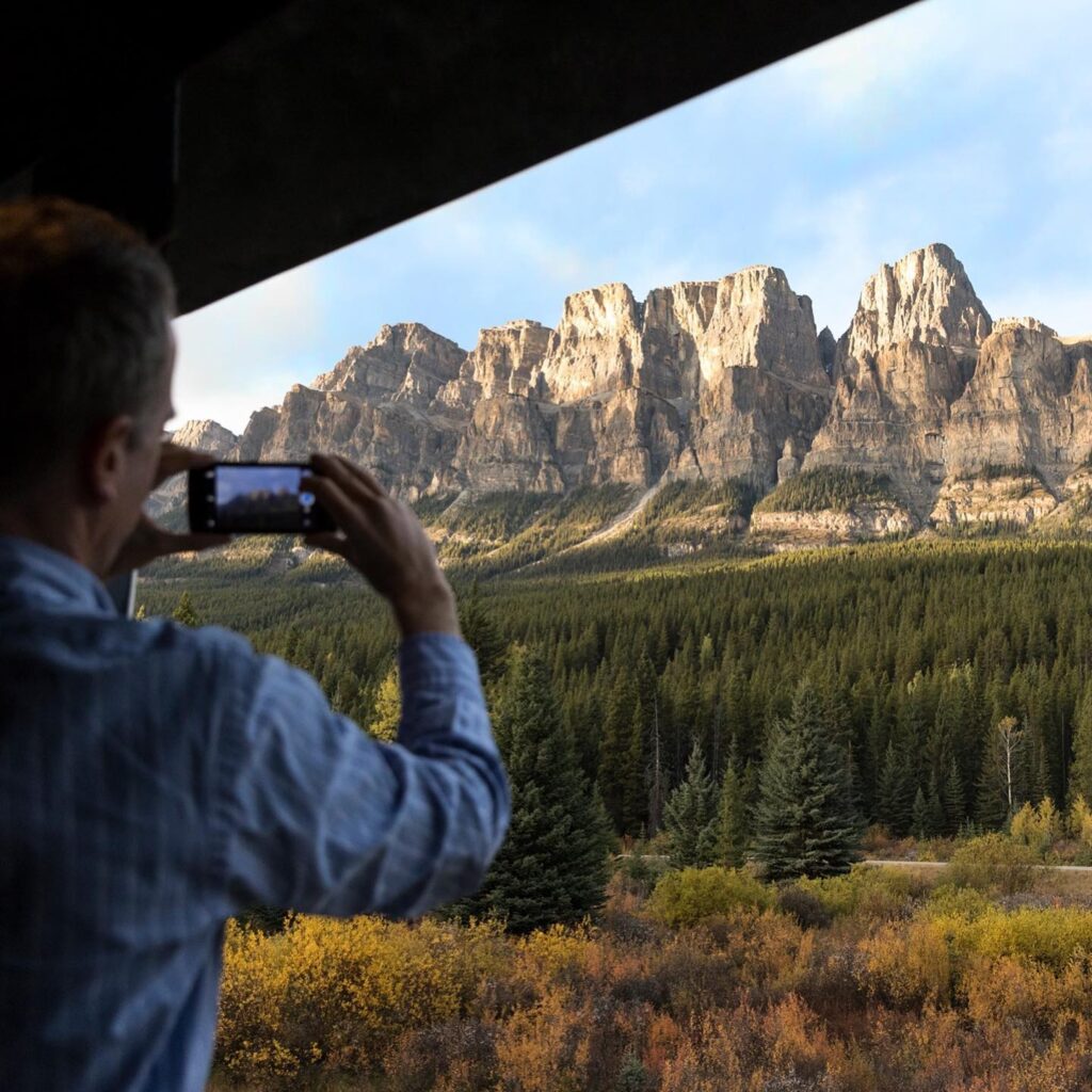 passenger taking a photo of the landscape aboard the Rocky Mountaineer