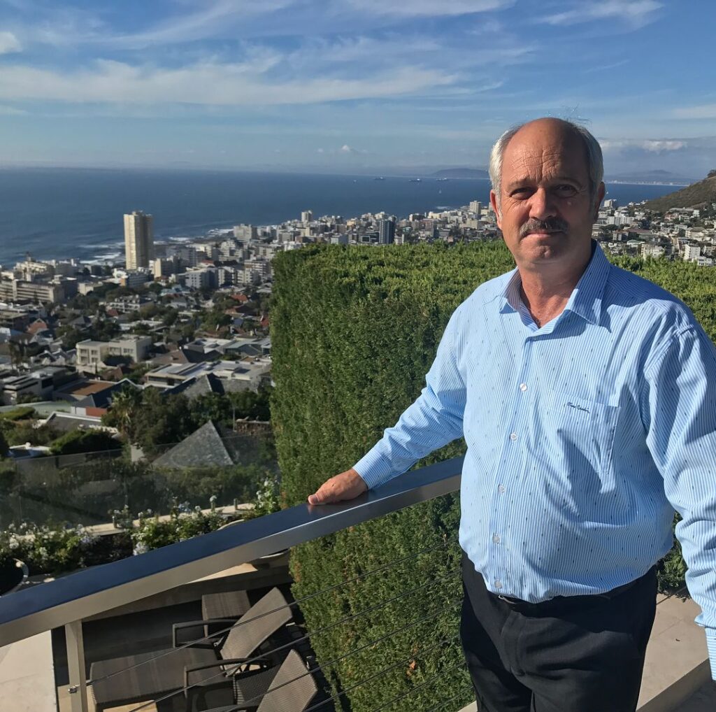 Image of Christo Brand standing at the edge of a terrace overlooking Cape Town with the ocean in the background