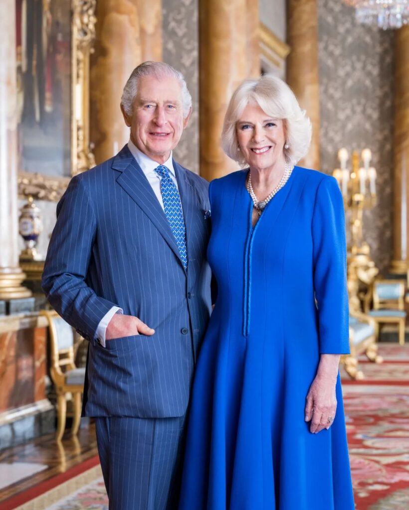 Image of King Charles III and Queen Camilla, smiling together in a star room of Buckingham Palace