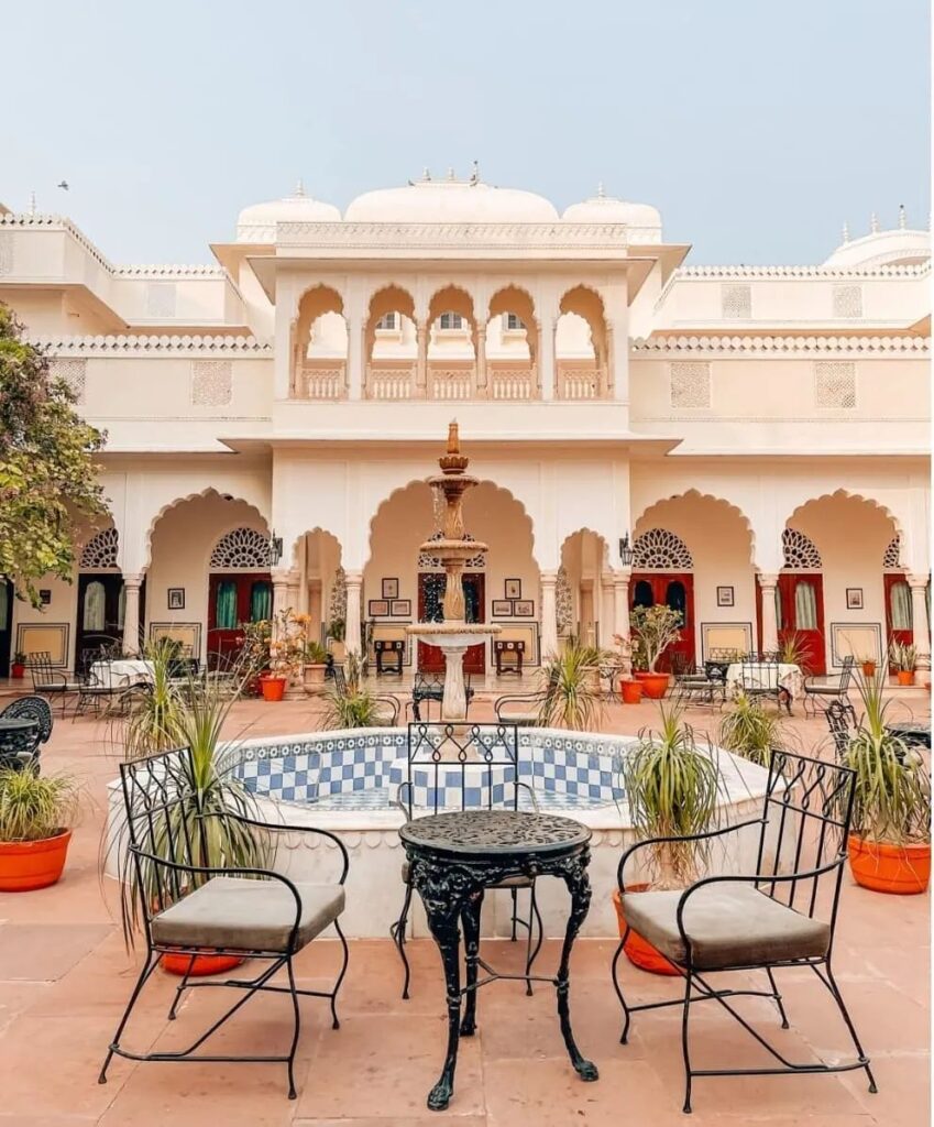 picture of chairs outside on the terrace of the Nahargarh Ranthambhore hotel, with the ornate architecture of the hotel visible in the background
