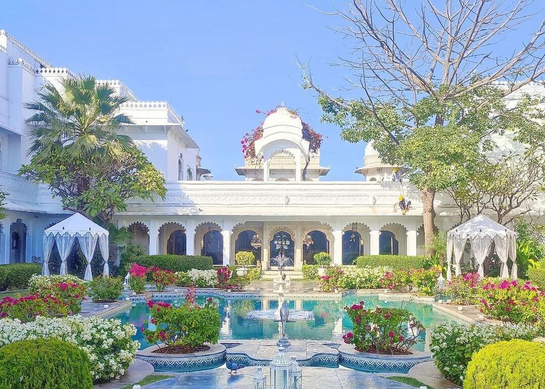 Image of Taj Lake Palace showing white marble building behind a colourful garden
