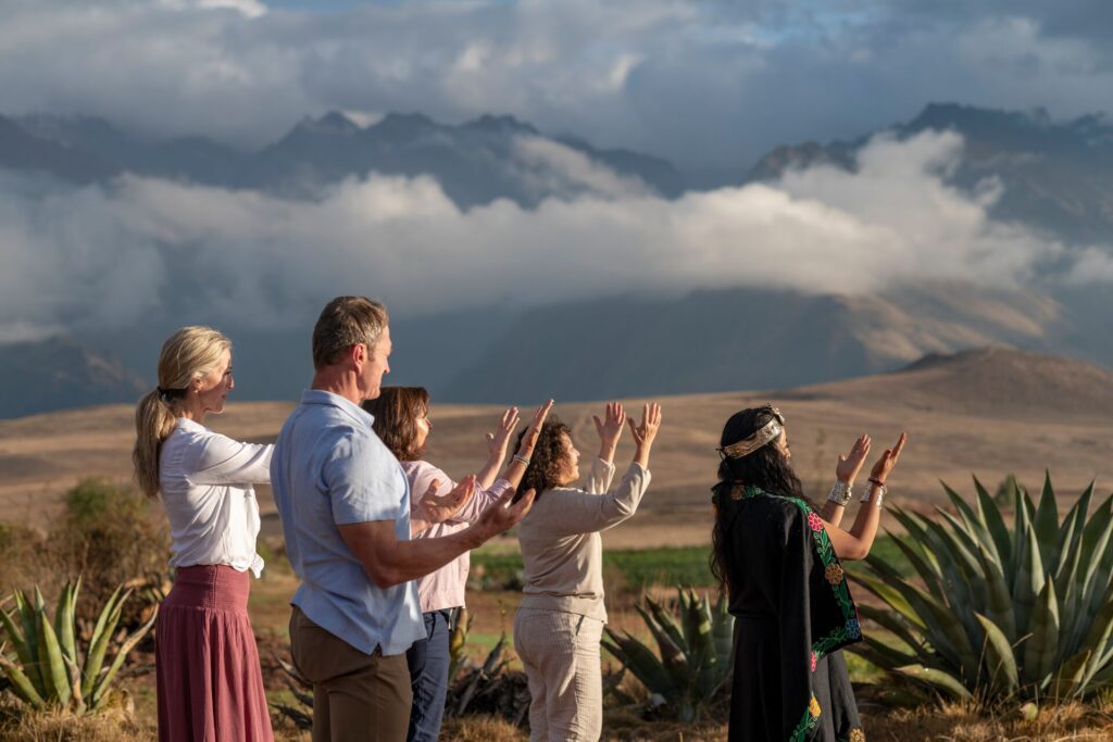Shaman Laura with guests holding hand up in a blessing, in the Peruvian Andes