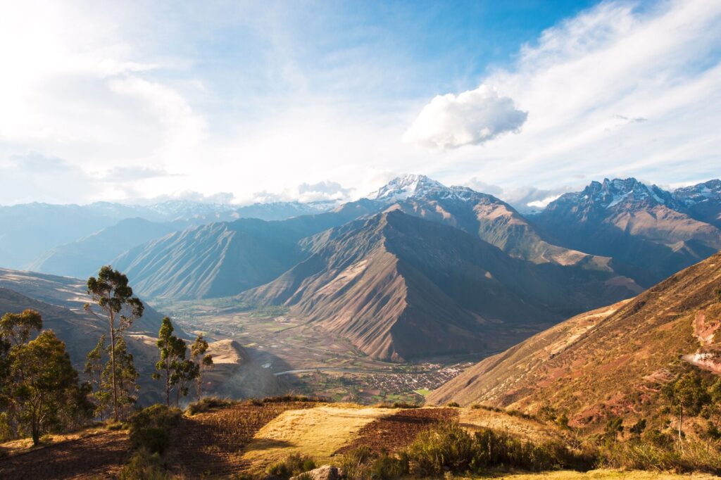 Image of Peru’s Sacred Valley, with mountains, red fields and a town in the bottom of the valley.