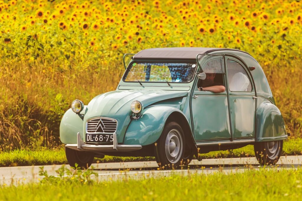 Vintage Citroen 2CV driving in front of blooming sunflowers in France