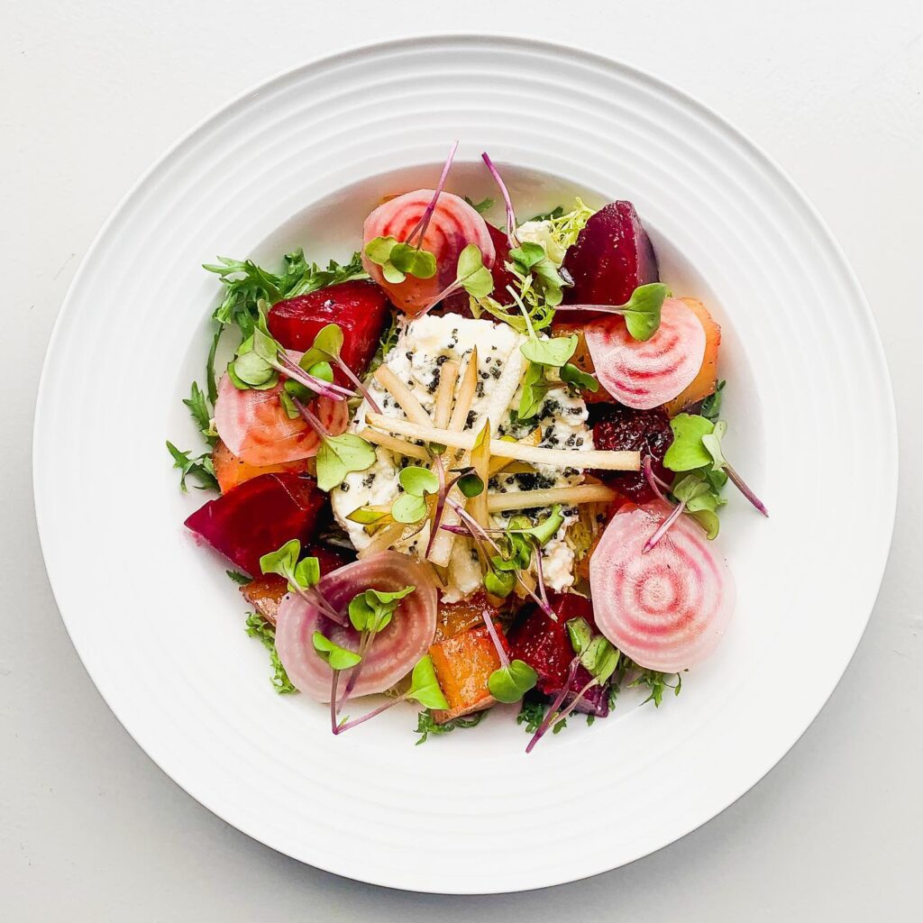 Image of a Play Food & Wine dish: red fermented pear garnished with colourful salad and pink radishes 