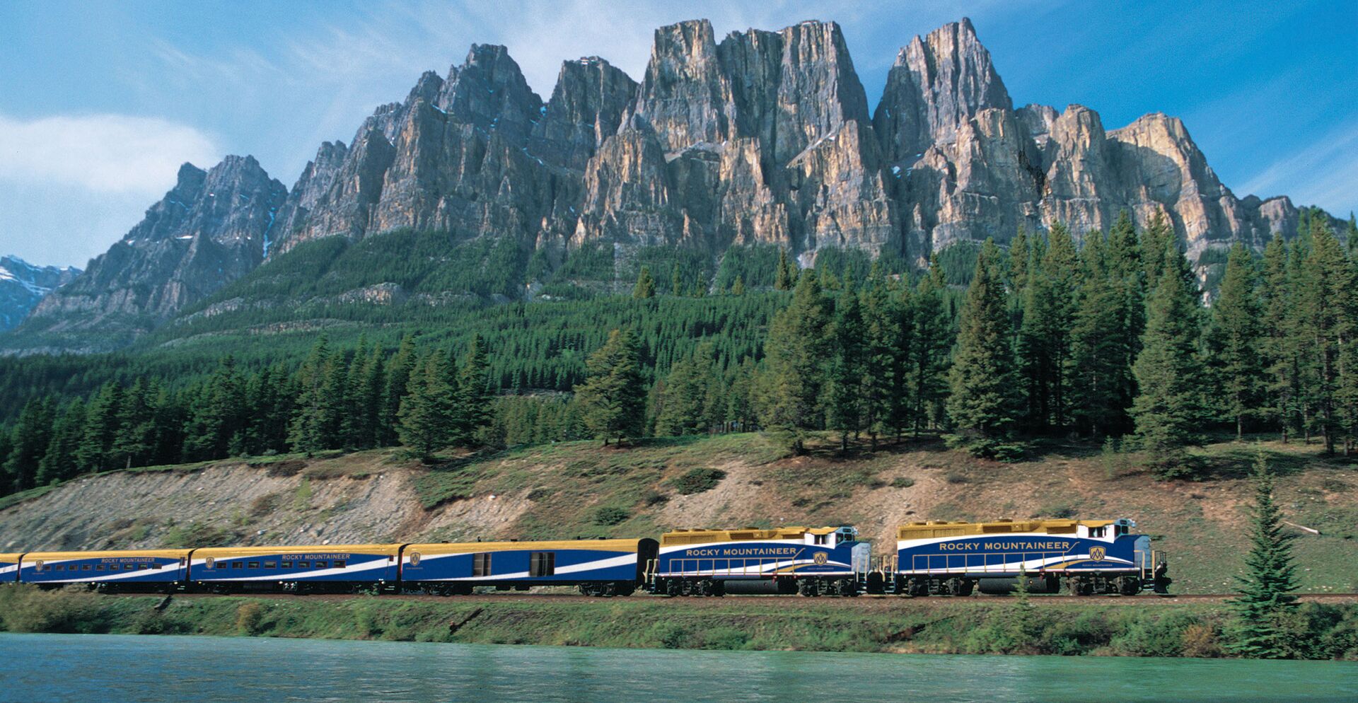 The Rocky Mountaineer train passing a lake and mountains 