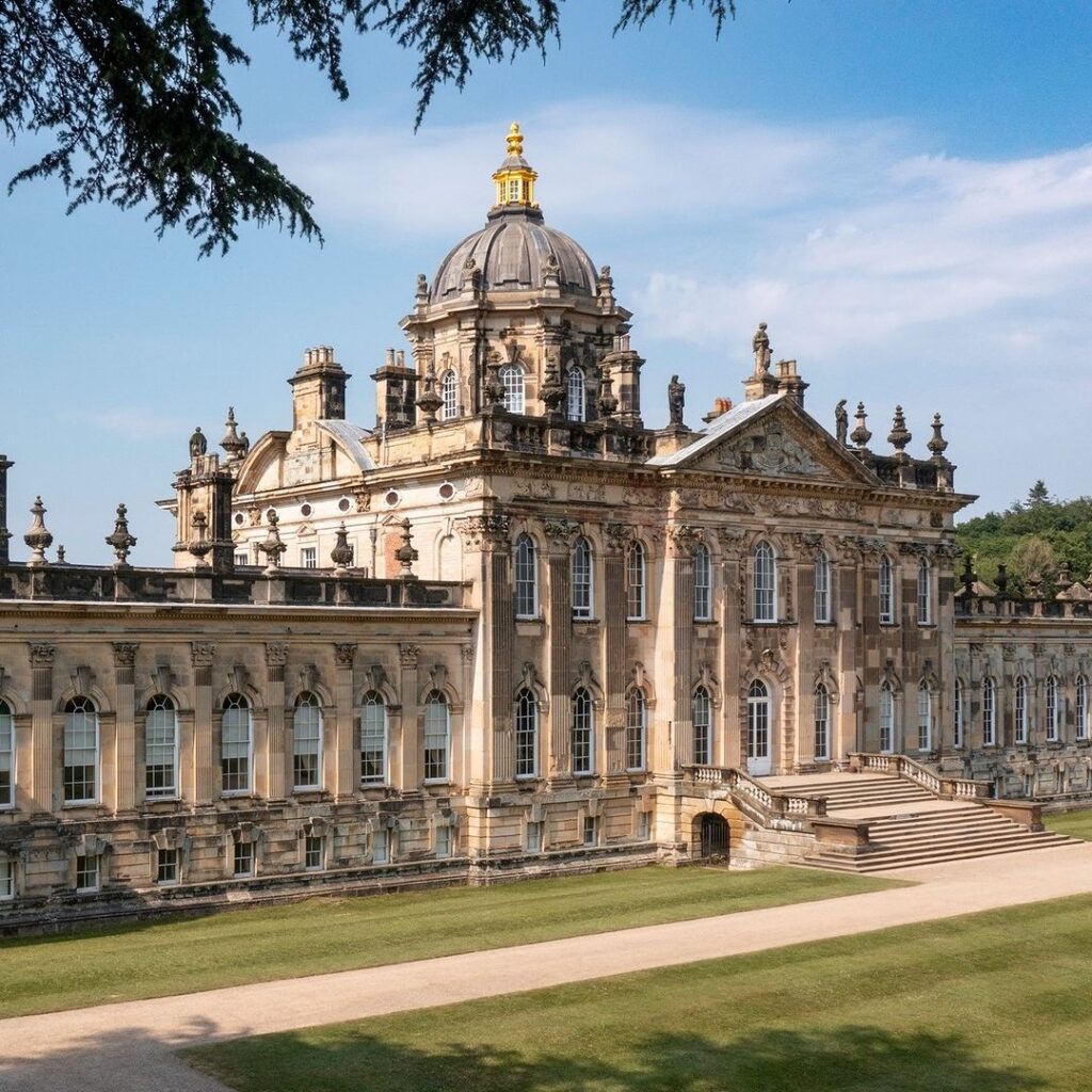 Image of the first of Castle Howard, ornate and decadent with the sun shining and green lawns in front