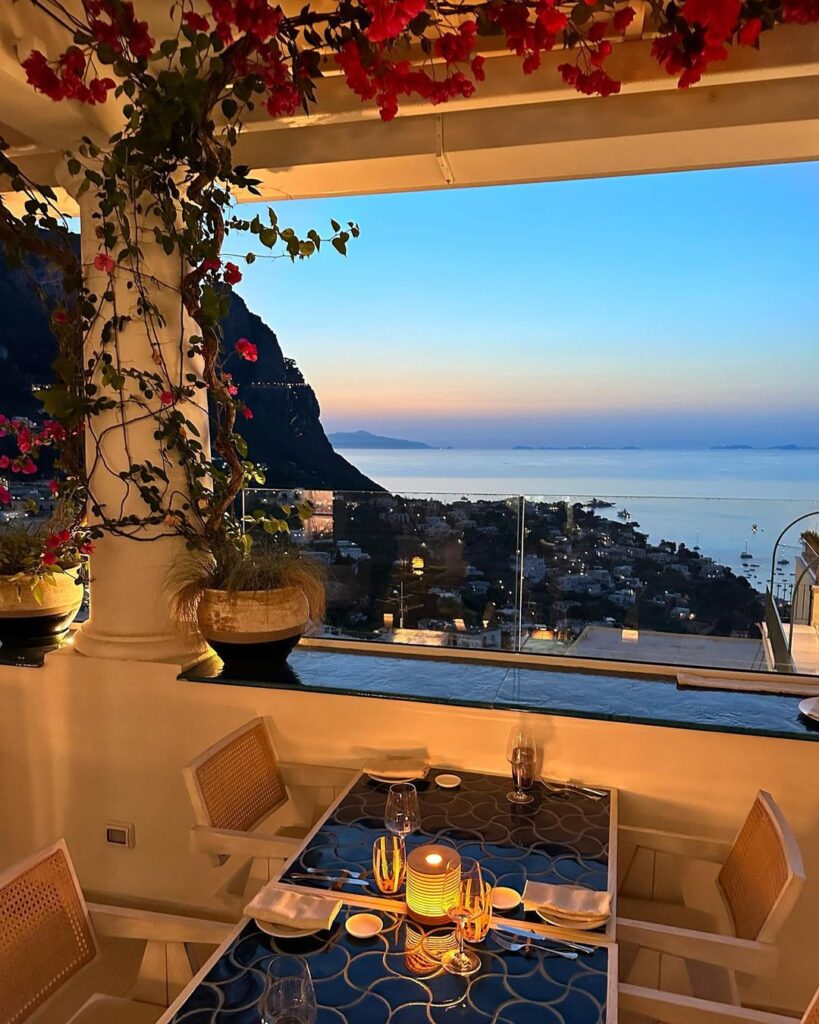 The view from a Mamma restaurant table on the Isle of Capri, a table is set against a window with a view over the gulf of Naples, as the sun sets