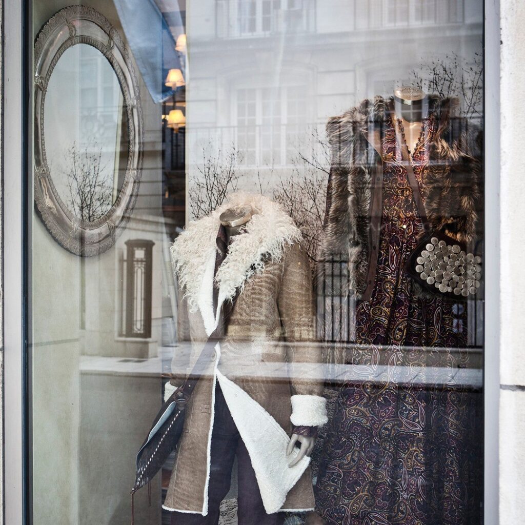 shop window on Avenida Alvear showing elegant rust coloured outfits with the grand architecture reflected in the window