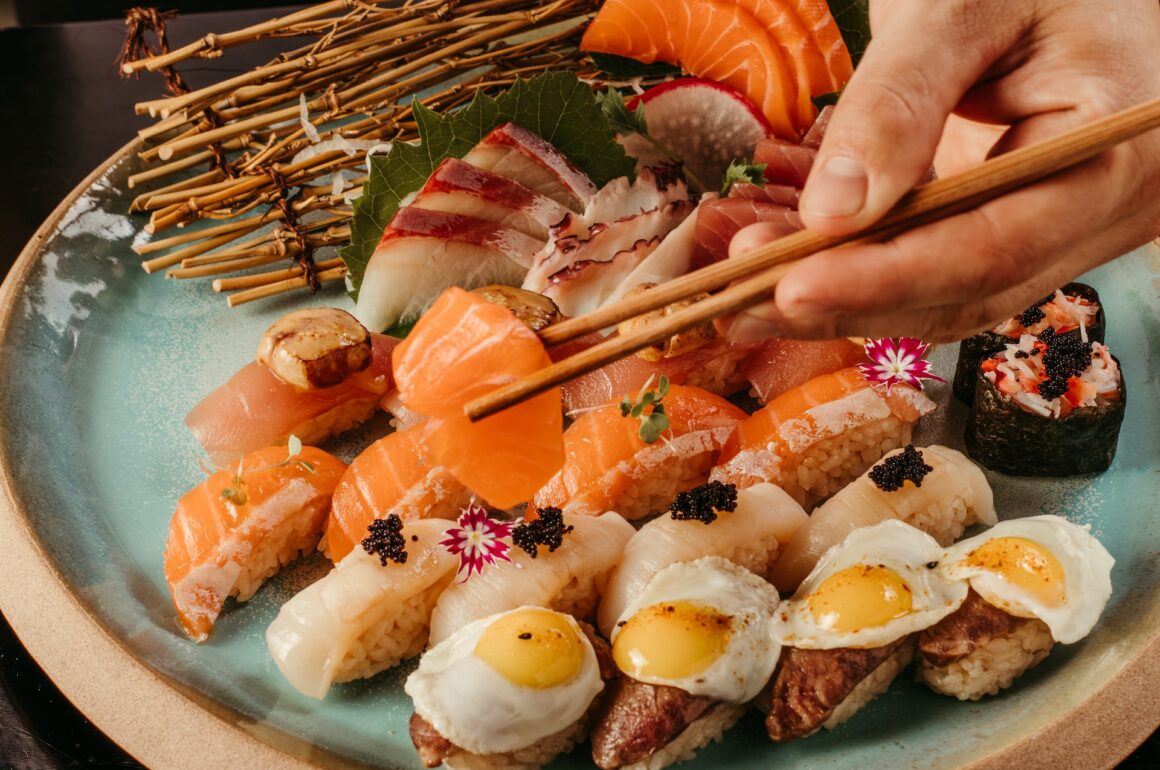 Plate of high-end sushi, with a hand holding chopsticks