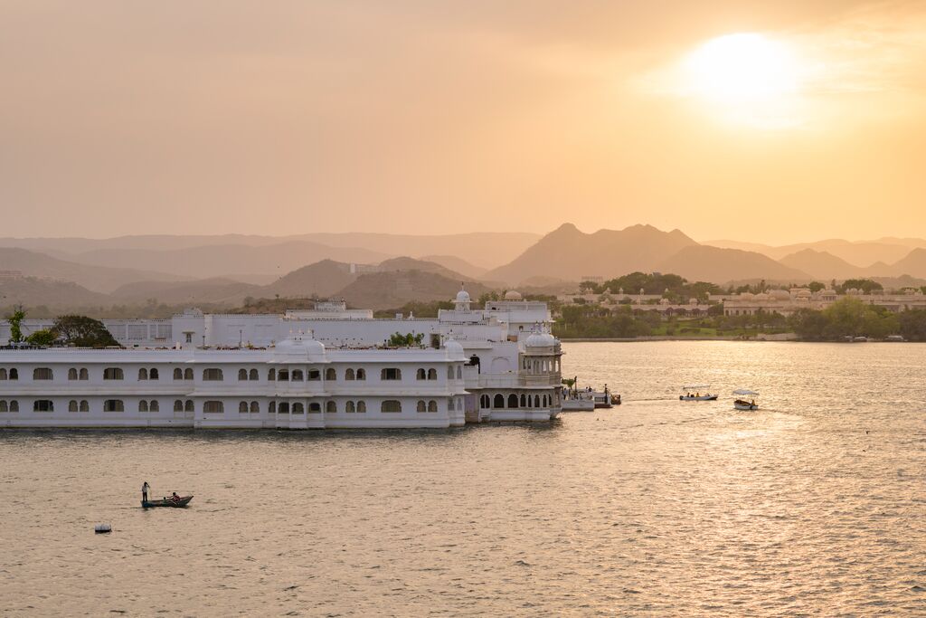 City Palace and Lake Pichola, seen at sunset, with distant hills silhouetted