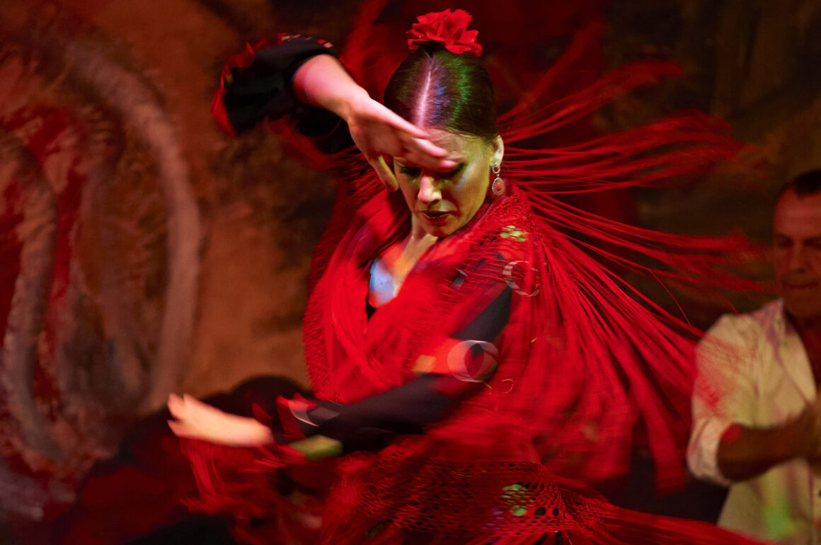 A flamenco dancer twirls with her red costume flaying out around her