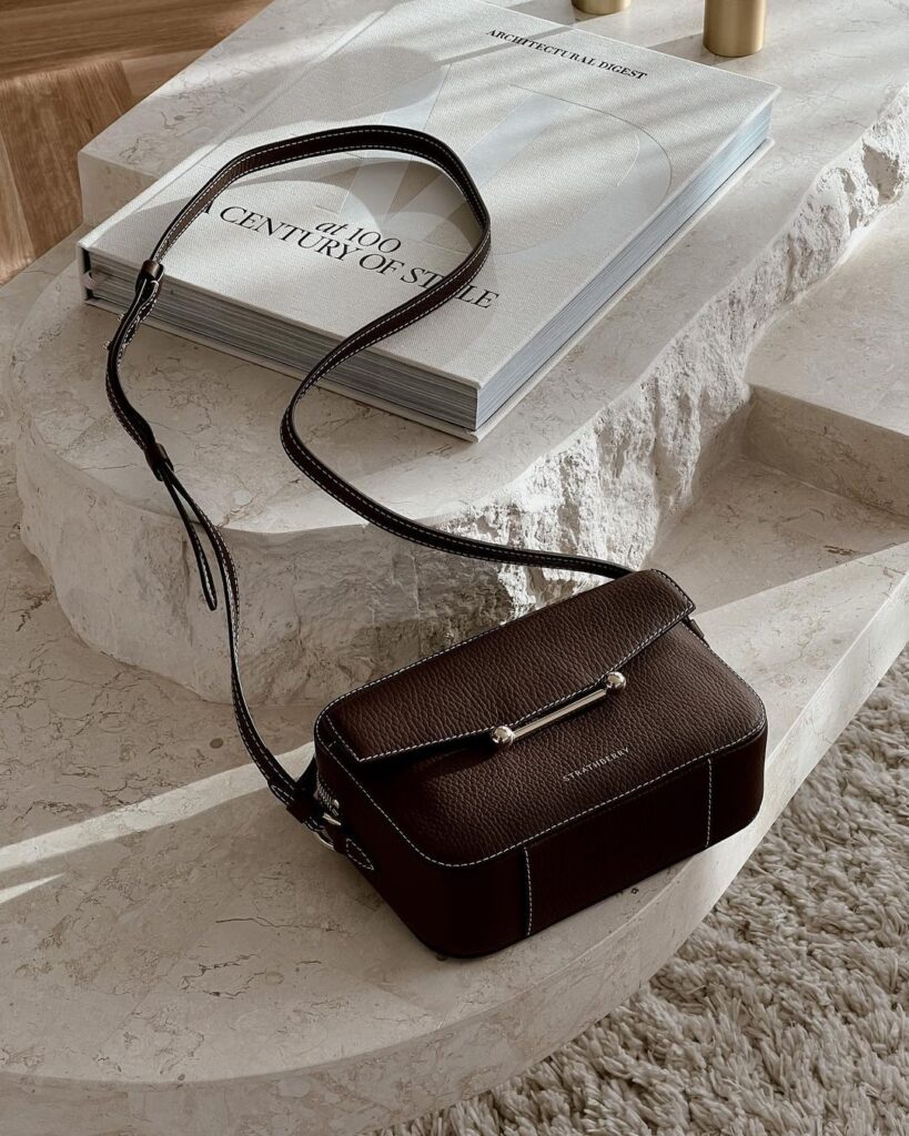 A brown leather handbag rests on white marble steps.