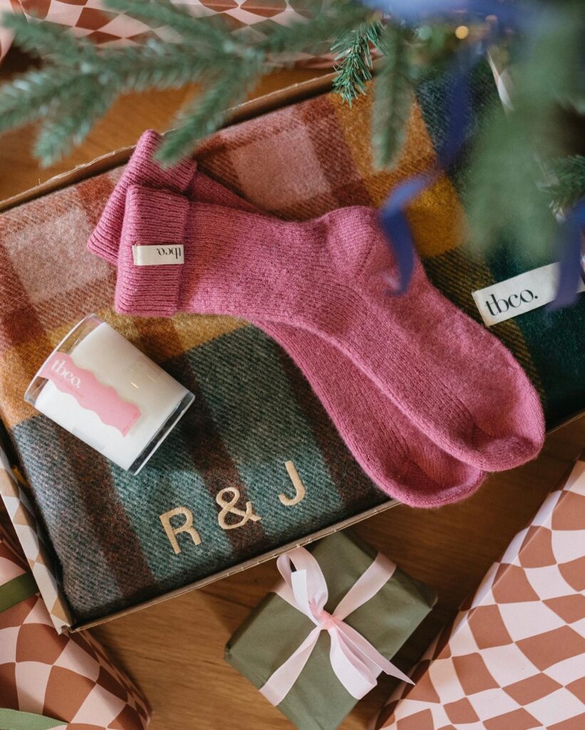 Socks and a scarf in tartan colours sit next to wrapped presents.