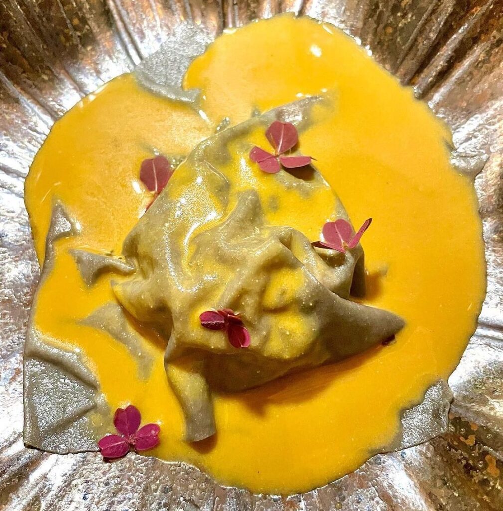 Plate of food awith yellow sauce and pink flowers at Manu Restaurant, Brazil