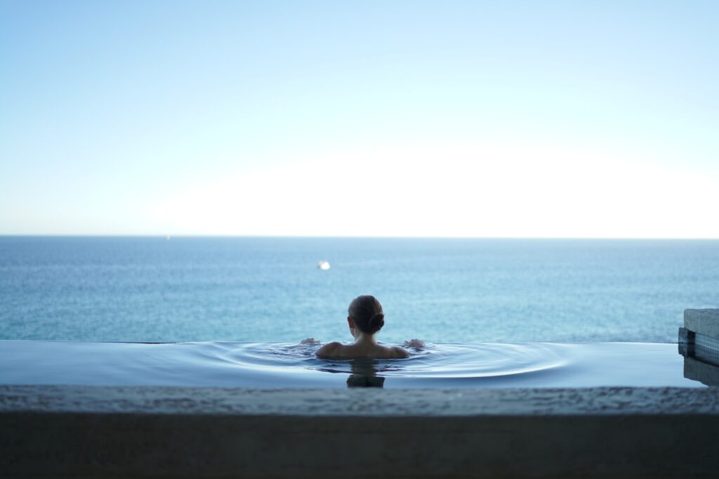 woman in an infinity pool overlooking the ocean