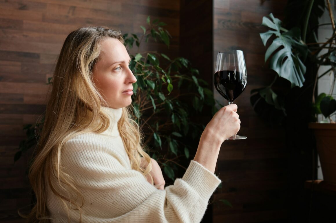 Female sommelier holding up a wine glass containing red wine